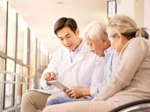 Asian senior couple in wheelchair consulting an asian male doctor