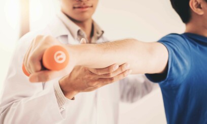 Mature caucasian adult patient strechtching his arm with the help of a male caucasian physiotherapist